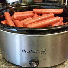 a crock pot filled with hot dogs sitting on top of a counter