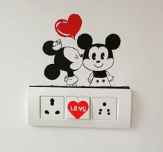 two mickey mouses are kissing on the light switch plate with a love heart sticker