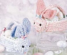 two crocheted stuffed animals sitting next to each other in front of a basket