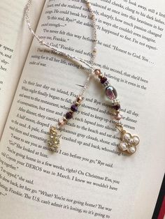 an open book with a necklace made out of pearls and beads on top of it