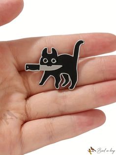 a hand holding a black cat with a knife in it's mouth