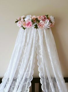 pink flowers are placed on top of the sheer curtain in front of a crib