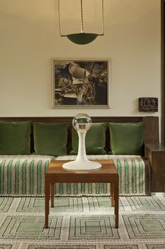 a living room filled with furniture and a painting on the wall above it's coffee table