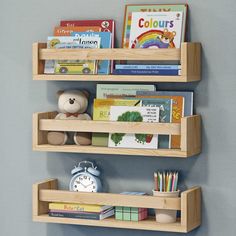 two wooden shelves with books and toys on them against a wall in a child's room