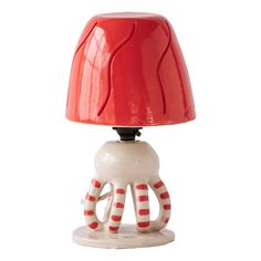 a red and white lamp with an octopus on it's base, sitting on a table