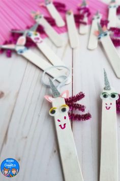 unicorn toothpicks are lined up on a white table with pink and purple decorations