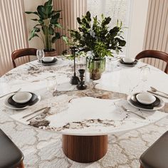 a marble dining table with place settings and plates on it, surrounded by potted plants