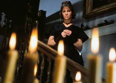 a woman is standing on the stairs in front of many lit candles