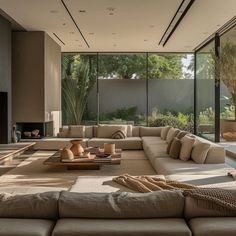 a living room filled with lots of furniture next to a large glass window covered wall