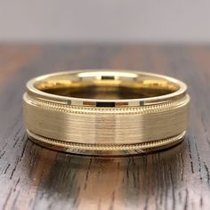 a gold wedding ring sitting on top of a wooden table