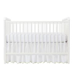 a crib with white bedding and pillows on the bottom row, in front of a white background