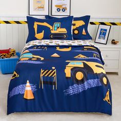 a bed with construction themed comforter and pillow cases on top of it in a room