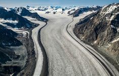 an aerial view of a glacier with mountains in the background