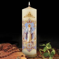 a lit candle with an image of the virgin mary on it next to some bread