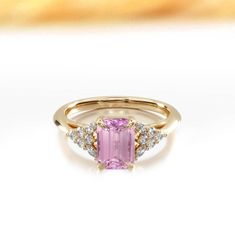 a pink tourmaline and diamond ring on a white surface with gold accents,