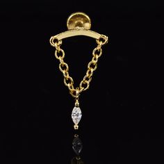 a gold chain ring with a white diamond hanging from it's center, on a black background