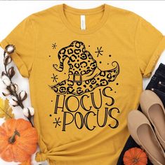 a t - shirt with the words hocus pocus on it next to pumpkins