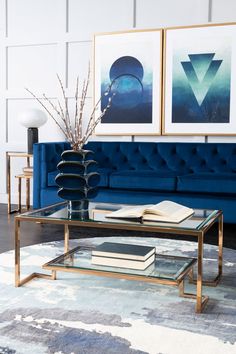 a living room with a blue couch and two pictures on the wall above it, along with a glass coffee table