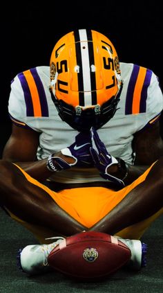 a football player sitting on the ground with his hands in his pockets and holding a ball