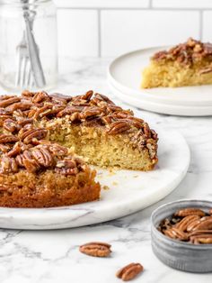 a piece of pecan cake on a plate with the rest of the cake in the background