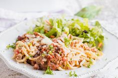 a white plate topped with pasta and lettuce