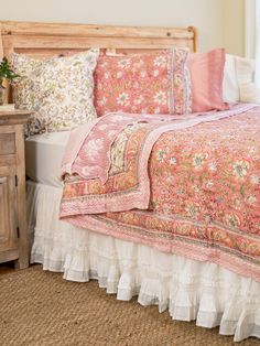 a bed with pink and white bedspread on top of it