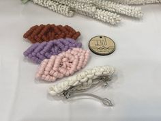 several crocheted hair clips laying on top of a white cloth covered table next to a button