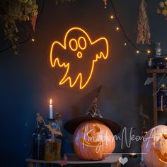 two carved pumpkins sitting on top of a table next to a lit up ghost