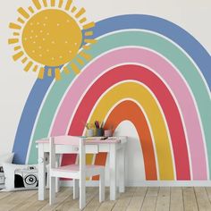 a child's room with a rainbow wall decal in the corner and a table for two