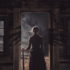 a woman is standing in an open doorway with a cane and looking at the sky