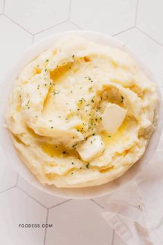 mashed potatoes in a white bowl with butter and seasoning on the side, top view