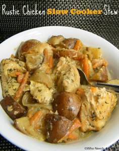 a white bowl filled with chicken, potatoes and carrots next to a black table cloth