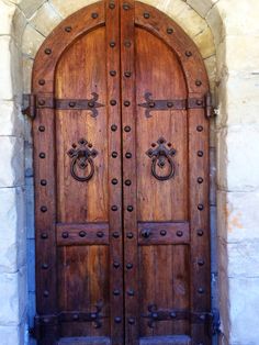 an old wooden door with metal handles on it's sides and arched doorways