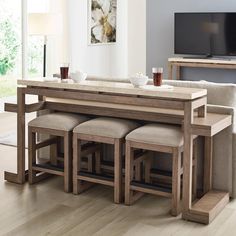 a dining table with four stools in front of it and a flat screen tv on the wall