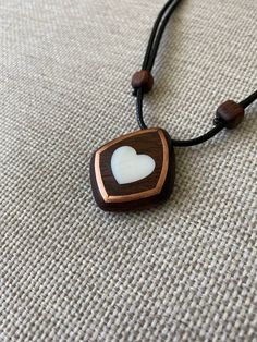 Size: 3.5 x 3 cm Immerse yourself in a world of romance with our elegant mahogany heart pendant with mother-of-pearl inlays. Every detail of this unique decoration embodies warmth and tenderness, creating a unique atmosphere. Our artisans carefully craft the pendant by hand, using only the finest materials. Mahogany adds natural warmth and sophistication, reproducing its unique patterns and textures. Mother-of-pearl inserts give the product a magical shine and a gentle glow that attracts attenti Handmade Mahogany Jewelry Gift, Handmade Mahogany Jewelry For Gift, Mahogany Handmade Jewelry For Gift, Handmade Mahogany Necklace For Gift, Unique Mahogany Jewelry For Gift, Mother Of Pearl Heart Pendant Jewelry Gift, Mother Of Pearl Inlay Jewelry For Gifts, Heart-shaped Brown Necklace For Gift, White Pendant Necklace With Inlay