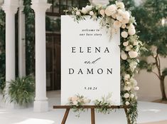 a wedding sign with flowers and greenery on it