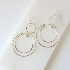 "Swinging circles and semi circles create these fun and unique earrings. Shown in sterling silver, also available in 14k gold fill and rose gold fill. Measure approximately 3\". All of my jewelry is made with sterling silver and gold fill wire and findings, nothing is plated and the craftsmanship is guaranteed, so feel secure in purchasing these earrings for yourself or as a special gift. I guarantee all of my work. All orders come packaged ready for gift giving. In order to keep down on waste, Modern Nickel-free Open Circle Hoop Earrings, Modern Circular Hoop Earrings For Anniversary, Modern Circle Hoop Earrings For Anniversary, Modern Hoop Earrings For Anniversary, Modern Anniversary Hoop Earrings, Nickel-free Anniversary Hoop Earrings, Geometric Hoop Earrings, Earrings Round, Crafting Materials