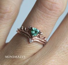 a close up of a person's hand wearing a ring with a green stone