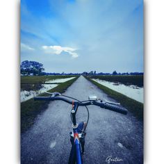 a bike parked on the side of a road next to an empty field with grass