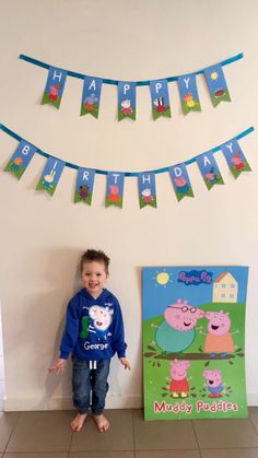 a little boy standing in front of a peppa pig birthday banner