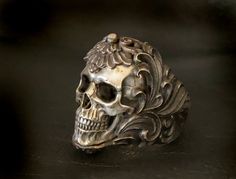 Ring Profile: 🔱 This is the heavy metal rock star of our skull rings. The hyper realistic skull is individually cast in 925 silver and embedded in an intricate floral ornament silver ring band to give the ring a contrasting dual-tone of silver. This eye-catcher skull ring is an absolute conversation-starter piece of work. 🔱 Customizable gemstone eye embellishment, please Contact Us for personal customization. 🔱 Available ring band finishes: | Polished | Dark Antique | Burnt Charcoal | 🔱 The Gothic Skull Ring For Formal Occasions, Formal Gothic Skull Ring, Formal White Gold Skull Ring, Silver Engraved Skull Ring, Floral Armor, Realistic Skull, Silver Ring Band, Skull Rings, Exotic Jewelry