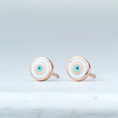 Handmade solid gold evil eye earrings, round shaped.  White evil eye set in 14k solid gold. Available in yellow, white or rose solid gold. The evil eye studs measure  7mm and have 14k solid gold posts and ear nuts. Simple eye catching minimal earrings great for everyday wear.  PLEASE NOTE THAT DHL EXPRESS SHIPPING MIGHT BE MORE EXPENSIVE OR NOT POSSIBLE FOR SOME REMOTE OR DANGEROUS AREAS White Gold Earrings With Diamond Eyes, White Gold Round Earrings With Diamond Eyes, White Polished Finish Earrings, White 14k Gold Earrings Tarnish Resistant, Symbolic White Round Jewelry, Silver Round Evil Eye Earrings, Sterling Silver Rose Gold Evil Eye Jewelry, Sterling Silver Evil Eye Jewelry In Rose Gold, Rose Gold Sterling Silver Evil Eye Jewelry