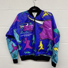 1996 Tyvek material windbreaker made by Leslie Jordan Inc. for the Fort Worth Cowtown Marathon. Bold and colourful graphic design shows people running with a bull.  Marked size Medium Armpit to armpit measures 21" Total length 24" Multicolor Sports Windbreaker For Spring, Multicolor Spring Sports Windbreaker, Spring Multicolor Sports Windbreaker, Fall Sports Windbreaker With Graphic Print, Urban Style Sports Windbreaker With Graphic Print, Leslie Jordan, Running 10k, People Running, Running Gear