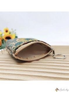 a small purse sitting on top of a wooden table next to a bouquet of flowers