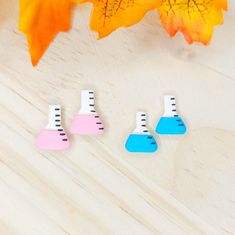 three small wooden pieces sitting on top of a white table next to leaves and a yellow leaf