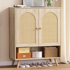 a wooden cabinet with two doors and some shoes on the bottom shelf next to it