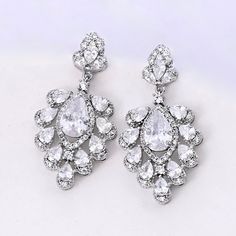 A unique pair of bridal earrings with an incredible sparkle! Adorned with flawlessly faceted cubic zirconia that capture the light from every angle with a perfectly translucent appeal, the earrings are rhodium plated for a bright finish which enhances the intricate detailing and conveys a modern take on old elegance. Overall length of the earring is 1.5" (approx. 3.8cm). Width: 0.75" (approx. 1.9cm). Weight: 8.2g. Hypoallergenic - lead, nickel and cadmium free. This exquisite design will add a t Wedding Cubic Zirconia Earrings With Diamond Accents, Glamorous Diamond White Cubic Zirconia Earrings, Dazzling Crystal Earrings With Diamond Cut, Wedding Diamond Cut Crystal Drop Earrings, Wedding Sparkling Cubic Zirconia Diamond Earrings, Diamond White Cubic Zirconia Chandelier Earrings For Wedding, Wedding Chandelier Earrings In Diamond White Cubic Zirconia, White Crystal Diamond-cut Earrings, Dazzling Cubic Zirconia Chandelier Earrings For Anniversary