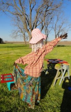 a woman wearing a hat standing in the grass with her arms spread out to catch a frisbee