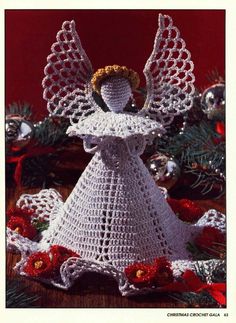 a crocheted angel is standing in front of christmas decorations