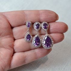 "These beautiful handmade classic amethyst purple cubic zirconia CZ teardrop dangle bridal earrings are available in three sizes and feature CZ halo pear drops dangling from CZ halo pear posts. The pear stones in the drops and posts are circled by a halo of small round brilliant cut CZs. All settings and findings are white gold and rhodium plated. These earrings are perfect for a romantic or vintage inspired look. Really beautiful quality and amazing sparkle perfect for your wedding or special occasion! For pierced ears.  Measurements: Small:  1\" L x 3/8\" W, bottom pear stone measures 6x8mm Medium:  1-1/4\" L x 1/2\" W, bottom pear stone measures 9x12mm Large:  1-3/8\" L x 3/8\" W, bottom pear stone measures 10x15mm Choose your size from the pull-down menu. I also have posts with clear s Crystal Falls, Sparkle Wedding, Jewelry Bridal, Jewelry Card, Wedding Jewelry Earrings, Amethyst Purple, Earring Findings, Matching Necklaces, Wedding Earrings